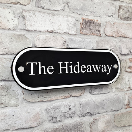 "Black House name plaque that says 'The Hideaway' on a wall"